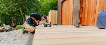 A contractor kneels to install light-colored Trex composite decking at a modern home in Lansing, Michigan. A contractor kneels to install light-colored Trex composite decking at a modern home in Lansing, Michigan.